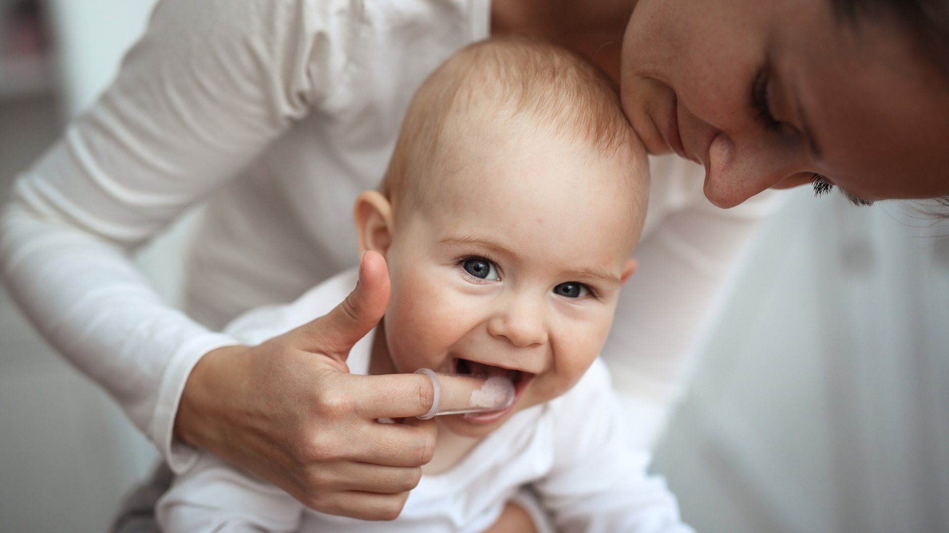 Mama czysci zeby malego dziecka szczoteczka na palcu
