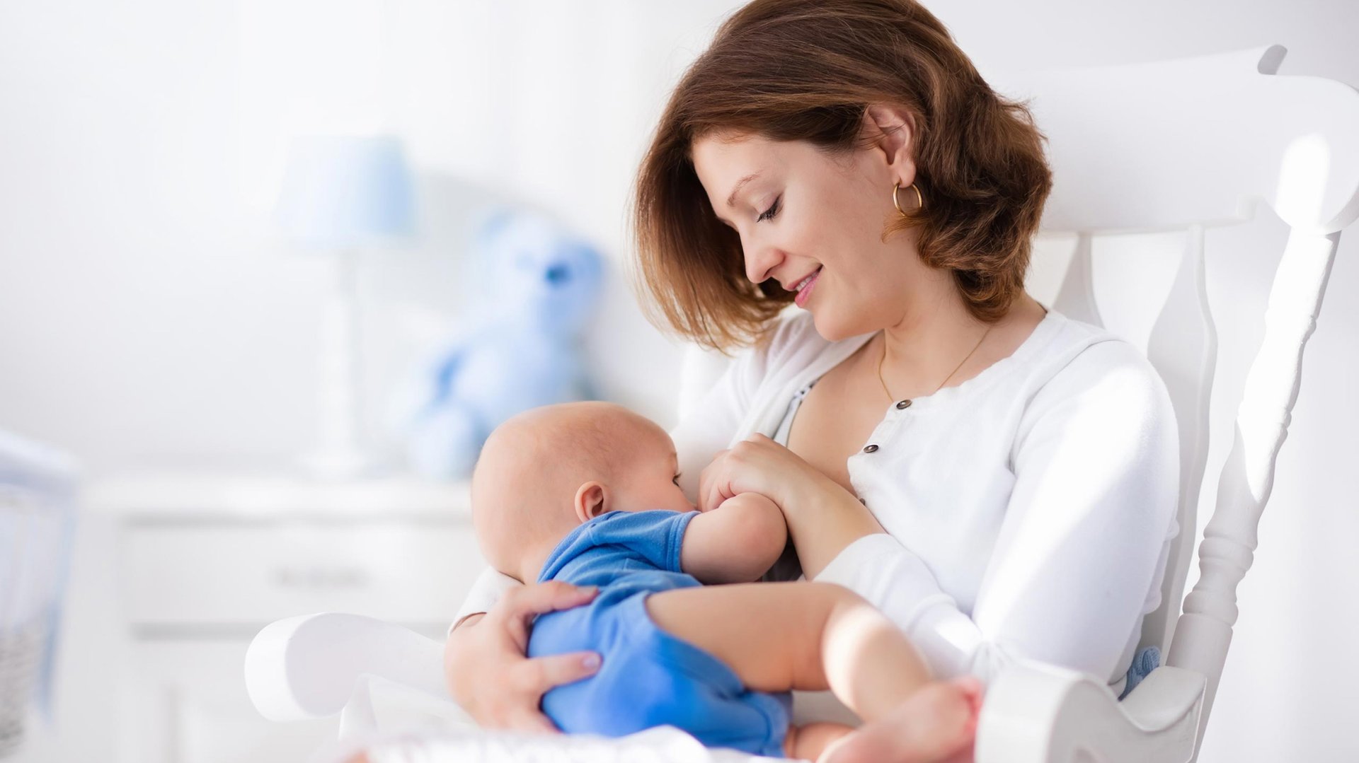 Mama siedzaca na bujanym krzesle karmi dziecko piersia