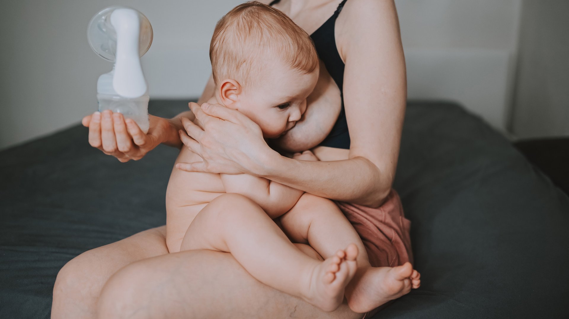 Mama karmi piersia dziecko trzymajac laktator w reku