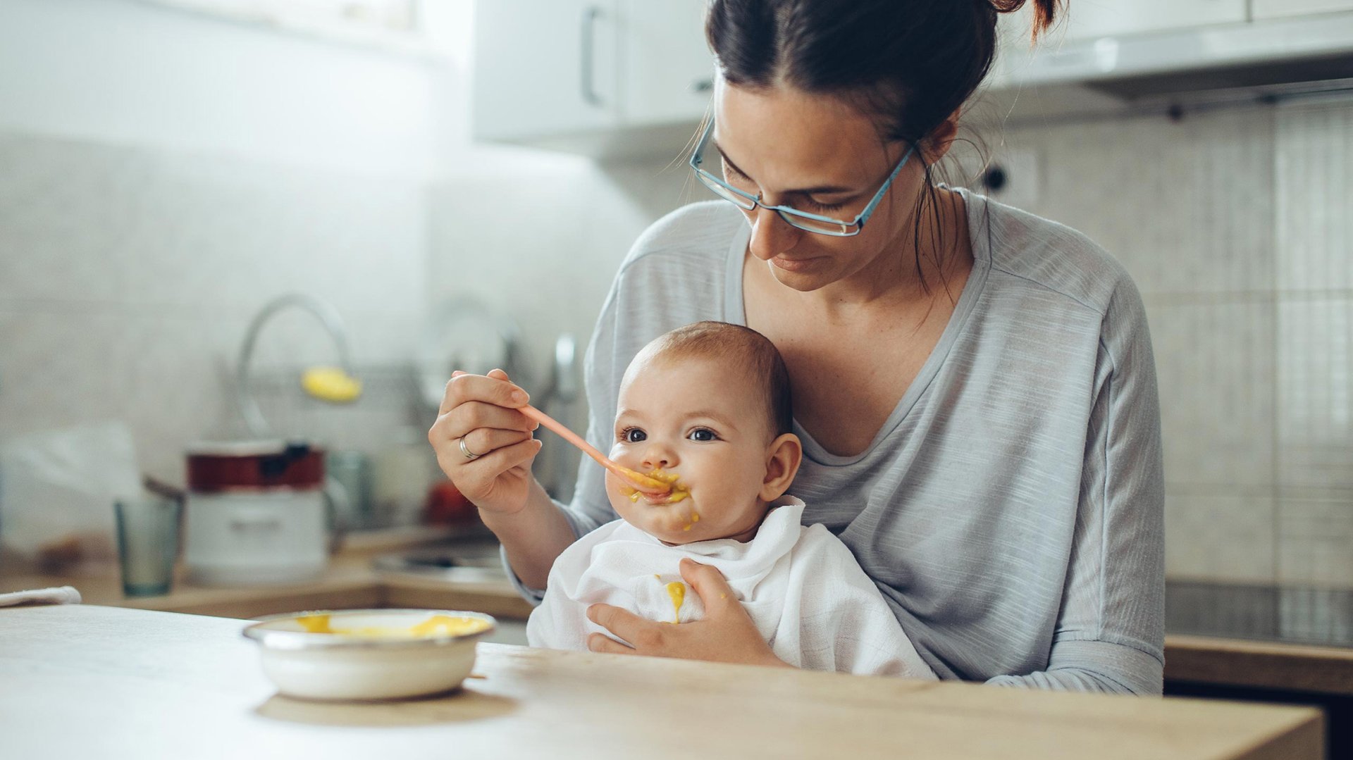 Mama karmi dziecko zupka z miski w kuchni