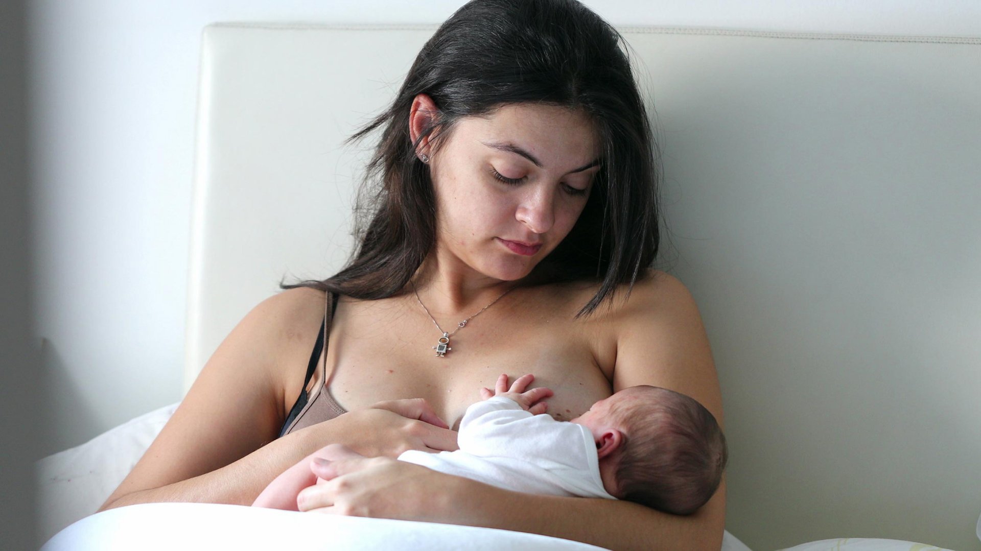 Mama lezy w lozku karmiac dziecko piersia