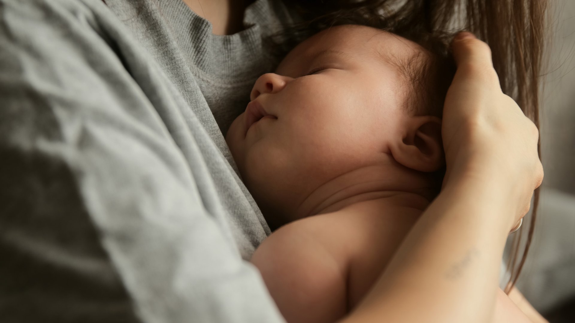Mama tuli dziecko do piersi trzymajac je za glowke