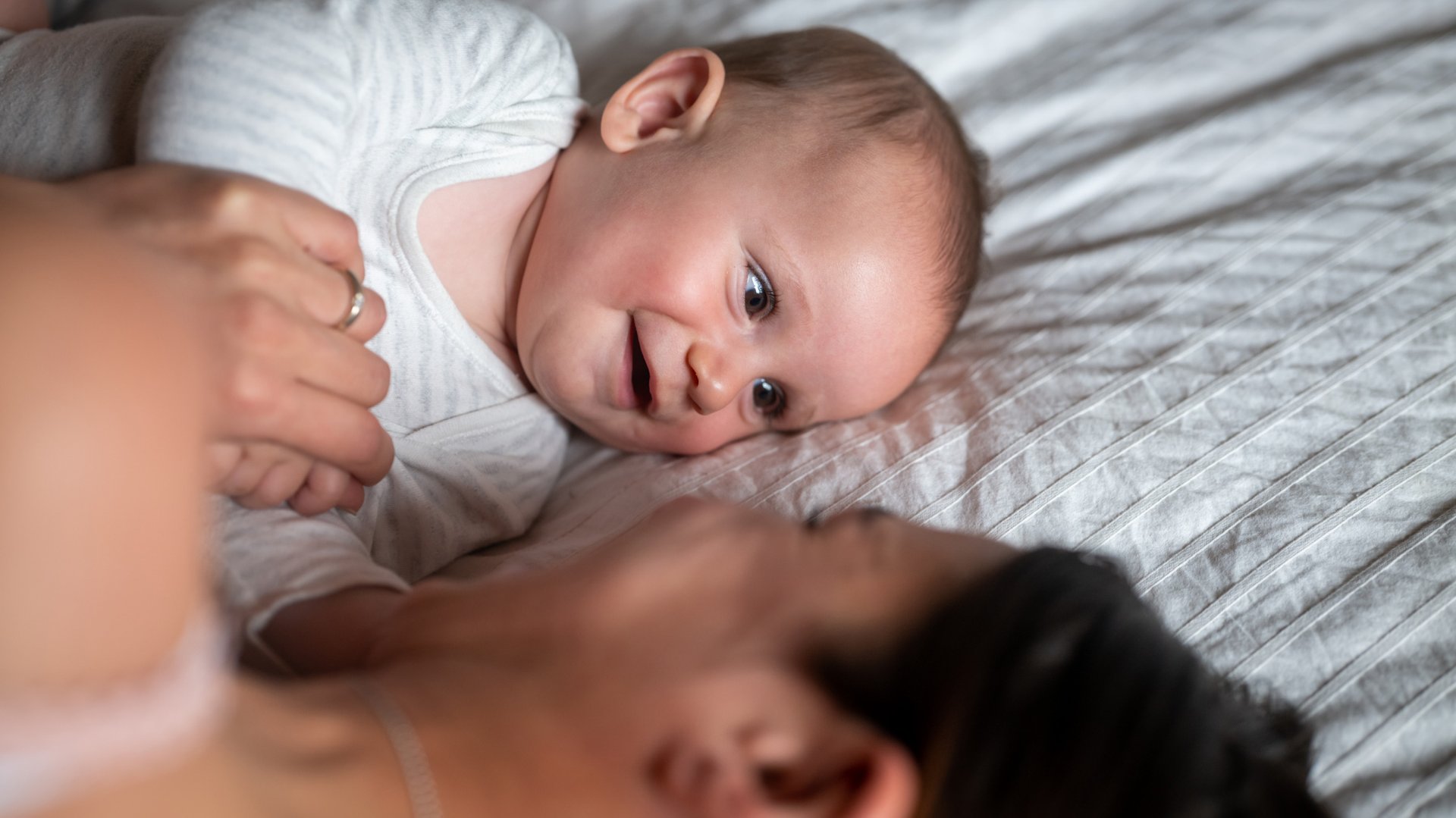 Mama i dziecko leza na lozku trzymajac sie za raczki