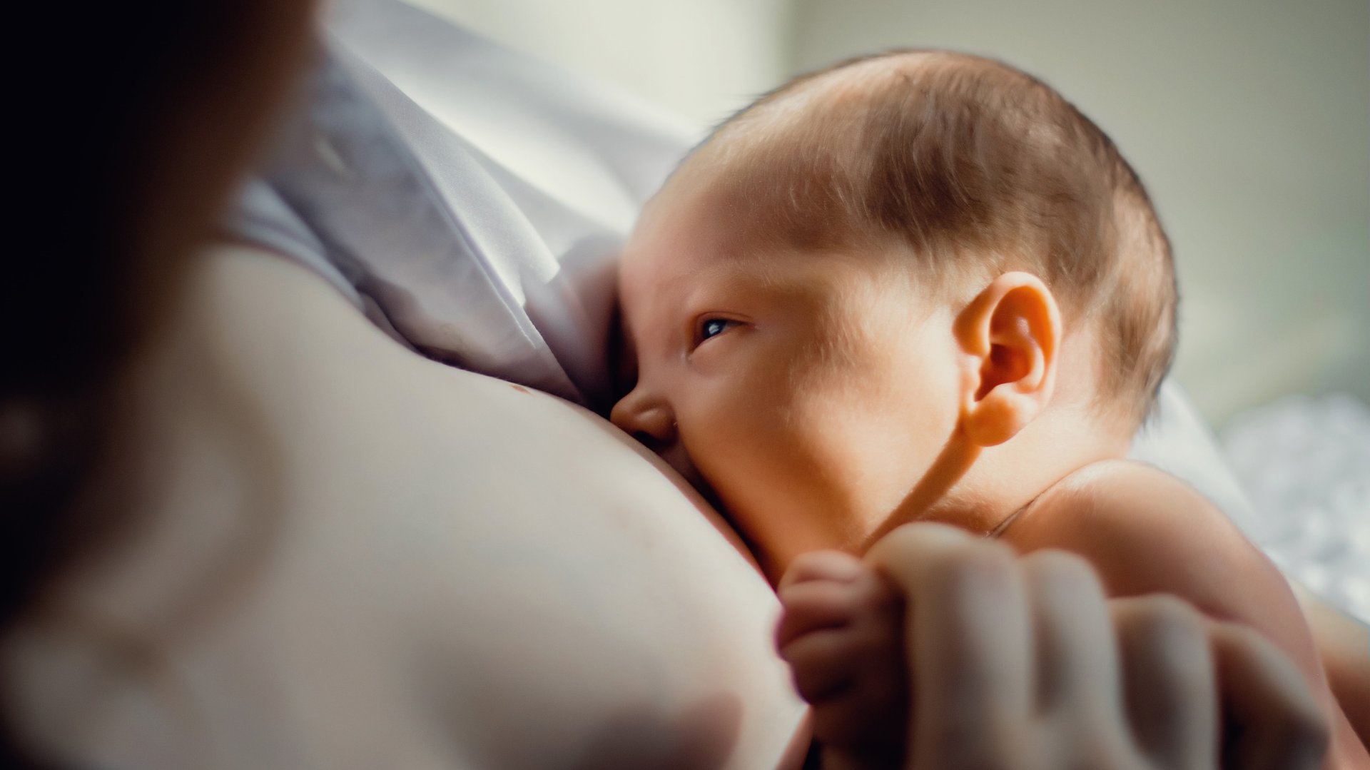 Mama karmi piersia dziecko trzymajc je za raczke