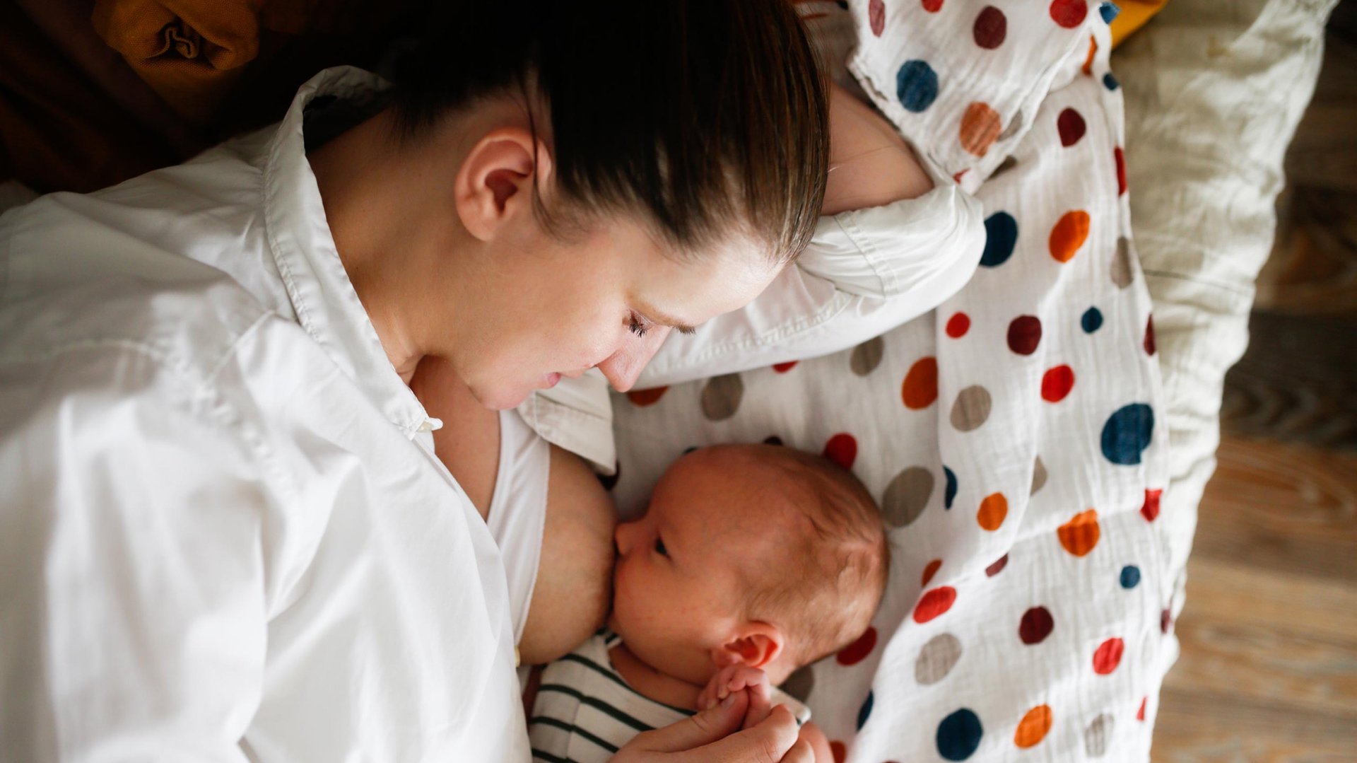 Mama karmi piersia niemowlaka lezac na boku