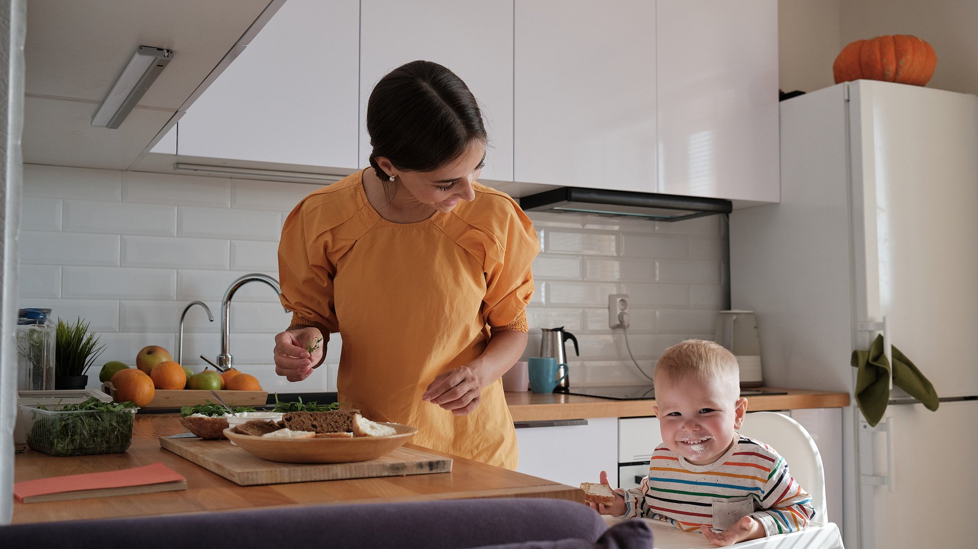 Mama przygotowuje posilek w kuchni z siedzacym maluchem